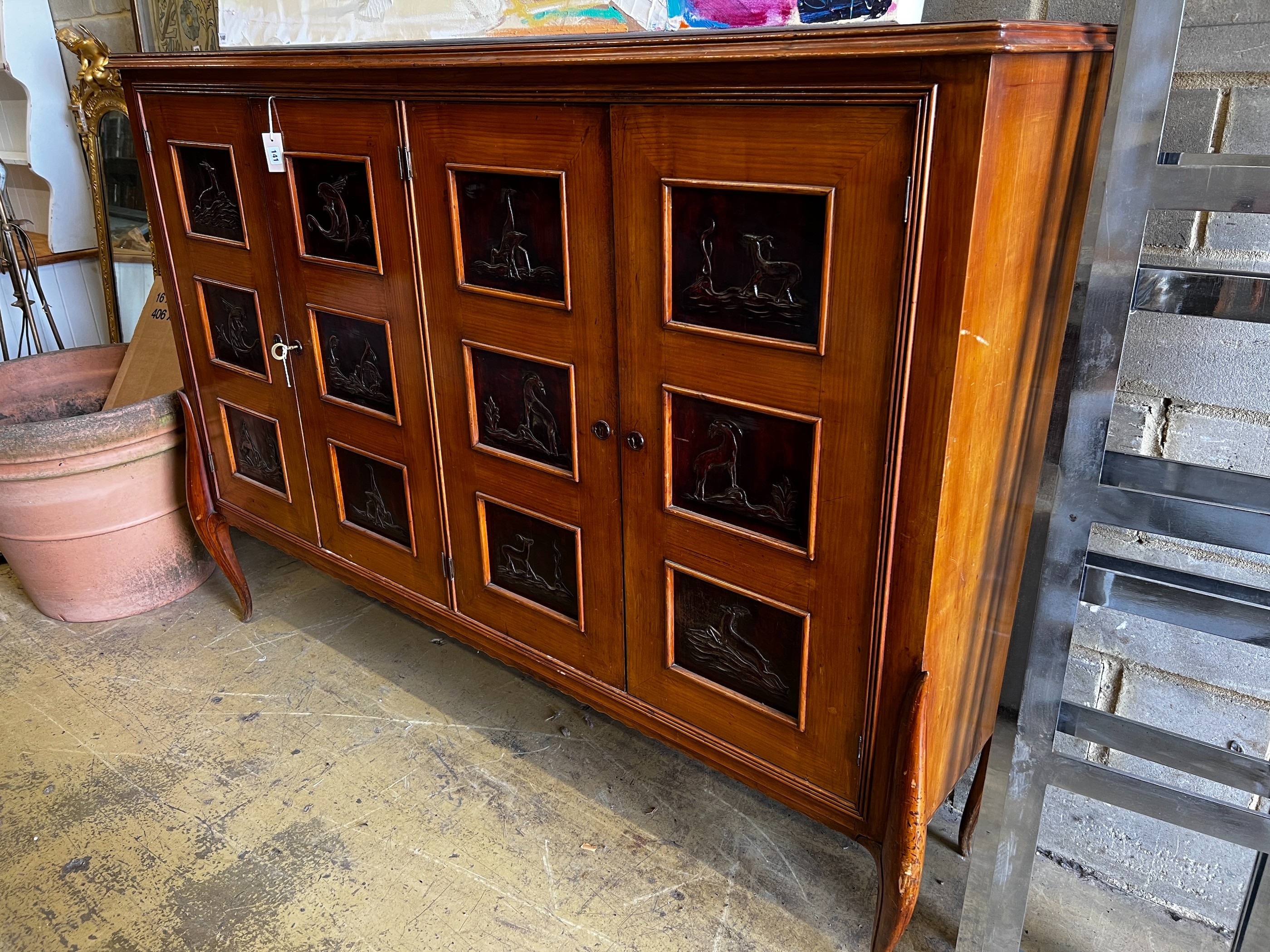 A mid century continental side cabinet, the panelled doors carved with antelope and exotic birds, width 212cm, depth 50cm, height 146cm